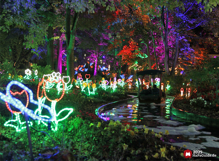 Blumenmeerbootsfahrt - Ein Boot passiert das Meer aus Lichtblumen und beleuchteten Baumkronen