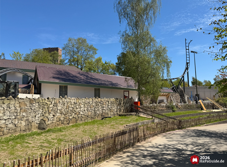 Cornwall Coaster im Hansa-Park: helles Durchfahrtsgebäude mit grünem Dachrand, Steinmauer und sichtbarer Achterbahnschiene unter blauem Himmel, Foto Mai 2026 von HaPaGuide.de