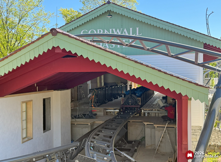 Cornwall Coaster im Hansa-Park: Achterbahnstation mit grünem Giebel und rotem Dach, sichtbarem Zug im Bahnhof und geschwungener Schiene, Foto Mai 2026 von HaPaGuide.de