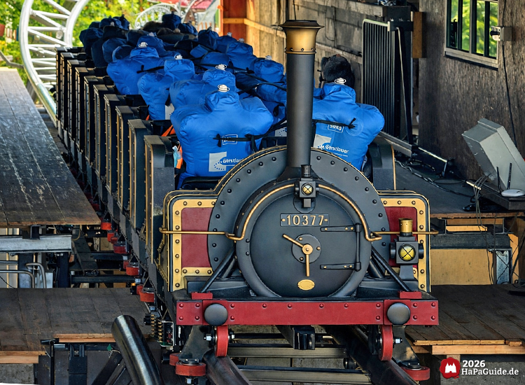 Cornwall Coaster im Hansa-Park: Zug im Stil einer historischen Dampflok mit der Nummer 10377 in der Station, blaue Testdummies mit GentleTour-Logo und sichtbarer Achterbahnschiene, Foto Mai 2026 von HaPaGuide.de