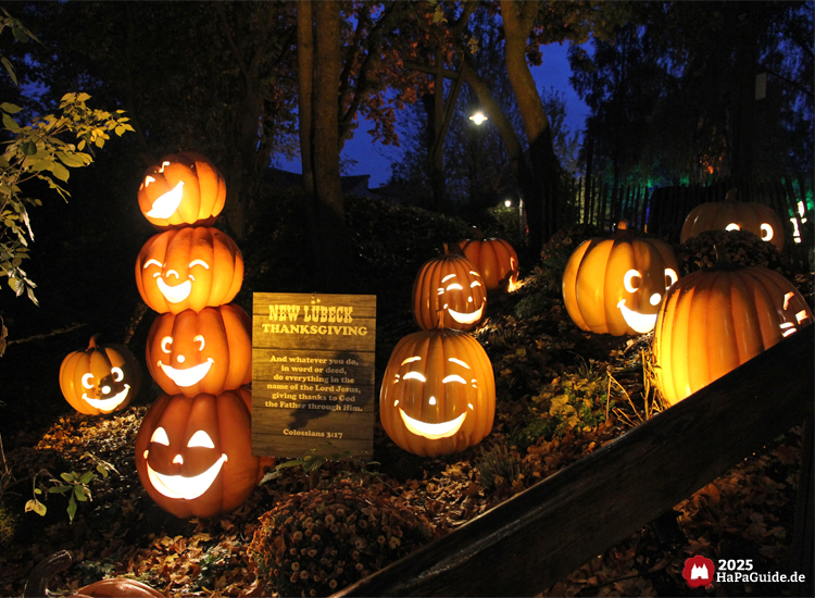 Beleuchtete Kürbisse während Erntedank im Hansa-Park bei Nacht mit lachenden Gesichtern und Schild New Lübeck Thanksgiving, warmes Licht zwischen Bäumen und Herbstlaub