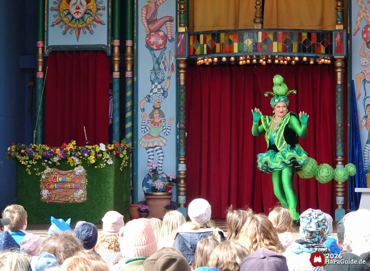 Schaubudenzauber - Eine Raupe grinst und winkt von der Bühne ins Publikum