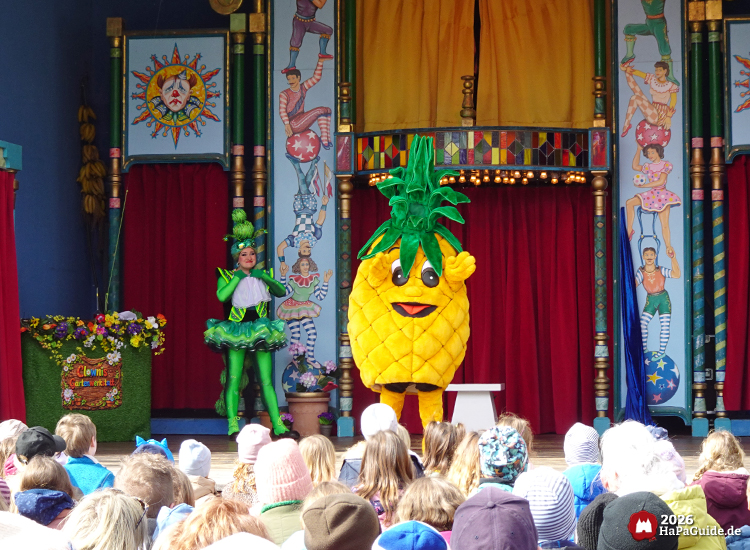 Schaubudenzauber - Eine Raupe steht neben einer Ananas auf der Showbühne