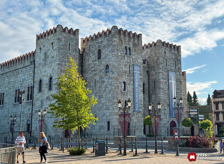 Palacio de Braga im Hansa-Park mit grauer Steinfassade und Zinnen, mittelalterlich gestaltetes Burggebäude mit Türmen, Bannern und Laternen im Vordergrund bei sonnigem Himmel