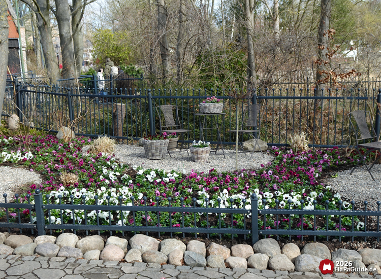 Frühlingsgarten mit bunten Stiefmütterchen, Sitzgruppe und dekorativen Blumenarrangements im Hansa Park