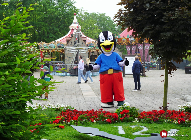 Maskottchen - Pinguin Pingi hinter der Blumenuhr />
                            <p class=