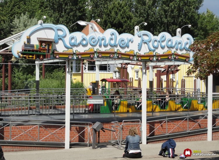 Ein Schild Rasender Roland über dem gläsernen Bahnhof