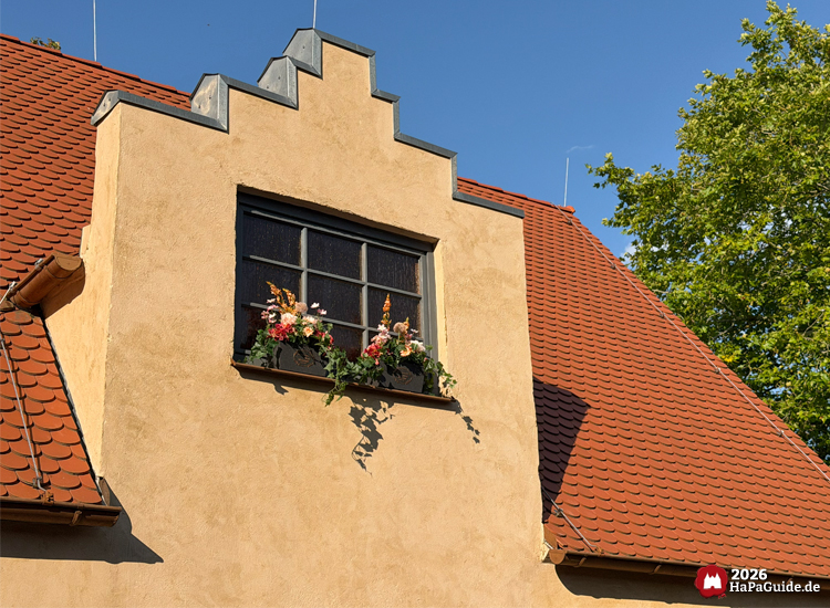 Stufiger Giebel des flämisches Hauses am Carrousel Baltique im Hansa-Park mit Fenster und farbig bepflanzten Blumenkästen unter Ziegeldach