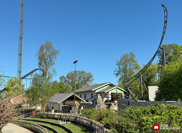 Cornwall Coaster 2026 im Hansa-Park – Familienachterbahn im Themenbereich Bezauberndes Britannien mit offenem Schienenende Spike, grün-weißen Gebäuden und Blick auf den Freifallturm Highlander bei sonnigem Himmel