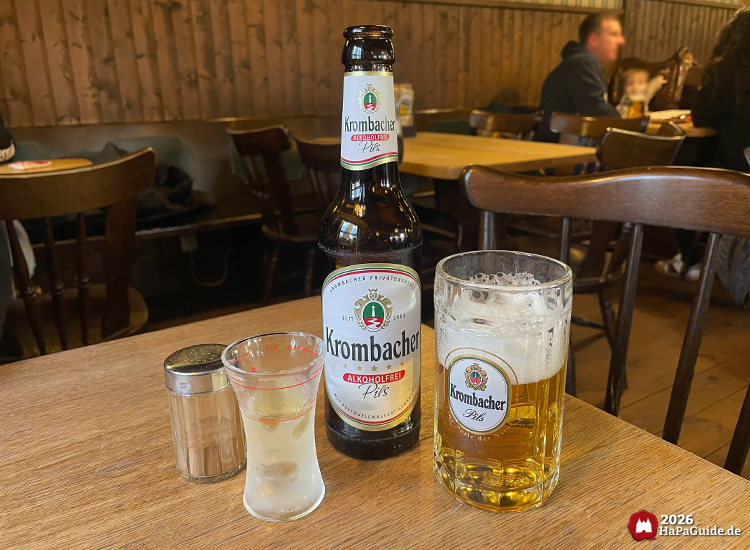 Krombacher Alkoholfrei Pils auf Holztisch im Saloon New Chance – Bierflasche, gefülltes Bierglas und Shotglas in gemütlicher Western Atmosphäre