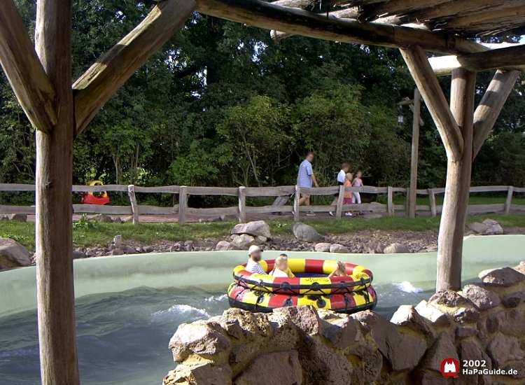 Ein rot-gelbes Rundboot treibt an einer Steinmauer vorbei