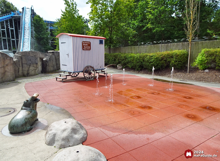 Wasserspielplatz Super Splash - Badekarren hinter Wasserfontänen